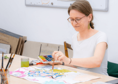 Slečna maluje akvarelem abstraktní arteterapeutickou malbu.